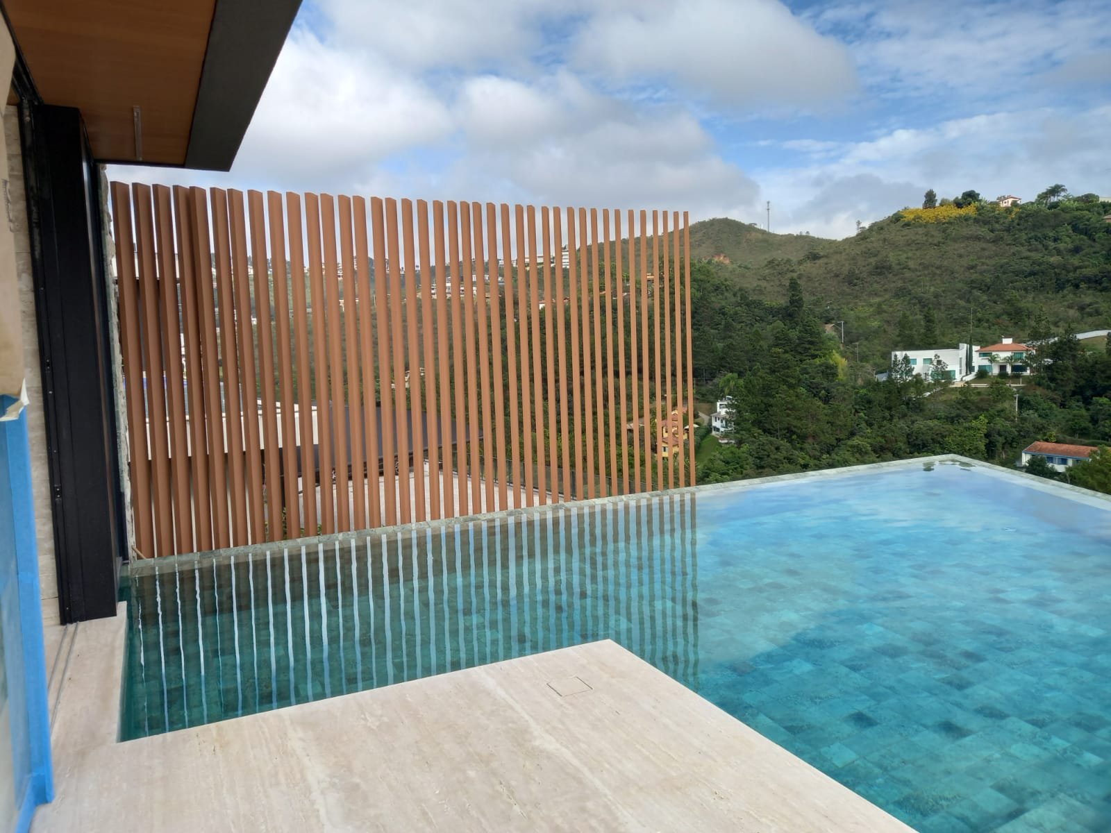 Piscina de borda infinita com deck de travertino e vista para o vale